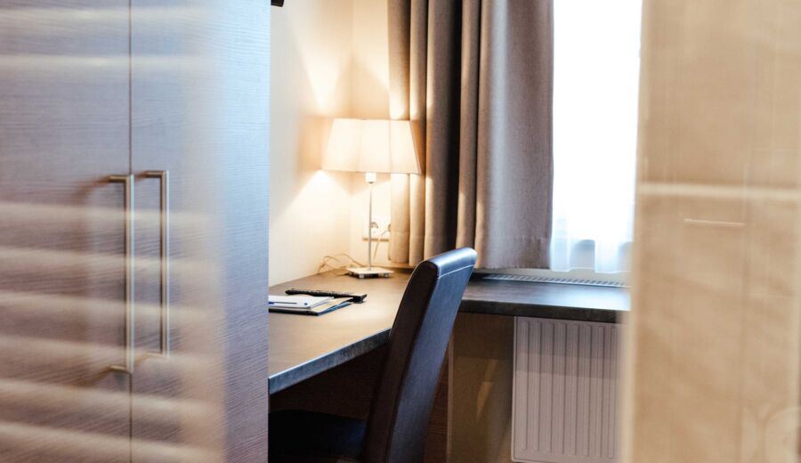 Ein Schreibtisch mit Leselampe im hellen Einzelzimmer des 4-Sterne hotels Kirchbichl