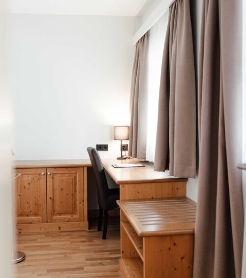 Das Doppelbettzimmer im Gästhaus mit einem Schreibtisch vor dem Fenster im Landgasthof Kirchbichl