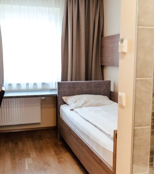 Single bed in single room with large window at Hotel Kirchbichl