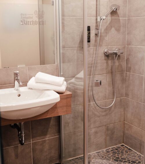 A walk-in shower and a washbasin in the bathroom of the twin room at the 4-star Hotel Kirchbichl