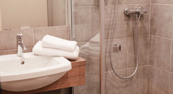 Eine Walk-In Dusche und ein Waschbecken im Badezimmer des Twinzimmers im 4-Sterne Hotel Kirchbichl